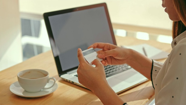 年轻的亚洲女子在网上购物与笔记本电脑和信用卡在咖啡馆视频素材