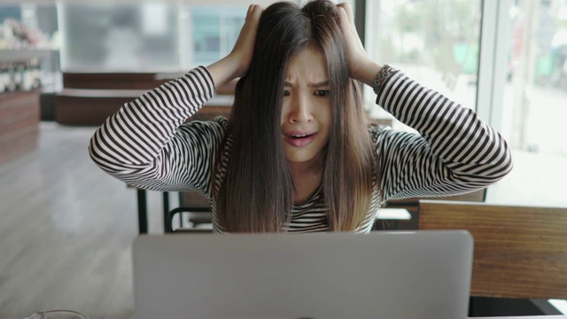 年轻的亚洲年轻女子震惊和反应损失的笔记本电脑在咖啡馆视频下载