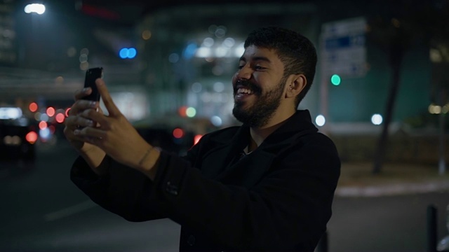 晚上在户外通过智能手机视频聊天的快乐男人视频下载