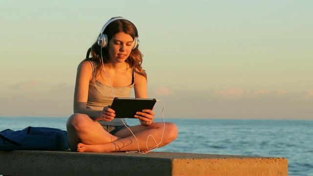 青少年放松，听着放松的音乐在日落视频素材