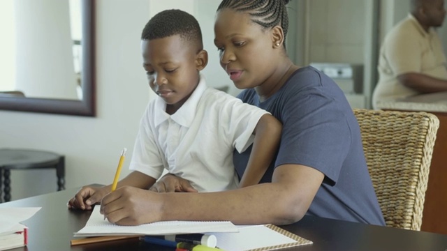 快乐的非洲妇女帮助她的儿子做家庭作业视频素材