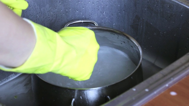 在厨房水槽中，用手用肥皂和水在黄色橡胶中洗锅视频素材