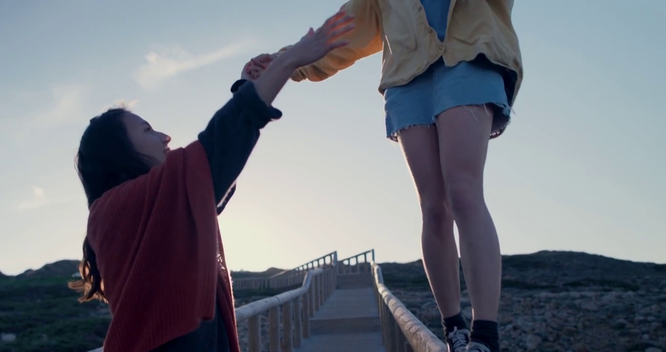 年轻女子在海滩人行道的栏杆上保持平衡视频下载