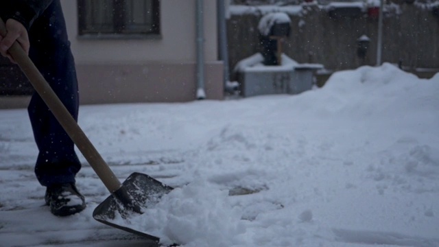 一个年长男子铲雪从他的后院的特写视频下载