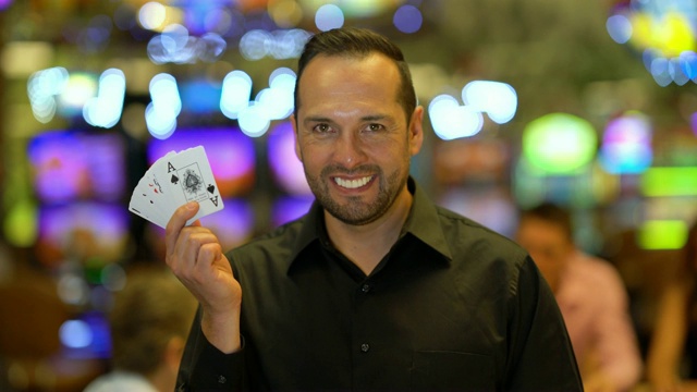拉丁美洲英俊的赌场经销商持有卡，而看着镜头微笑视频素材