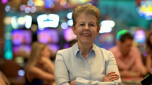拉丁美洲年长的女人在赌场看着镜头，双臂交叉微笑视频素材