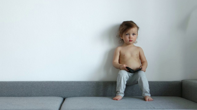 一个可爱的婴儿坐在灰色的沙发上视频素材