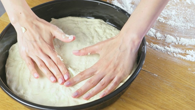 女人的手把酵母面团放在圆烤盘上。做披萨。视频素材