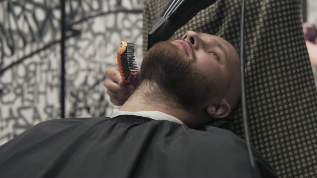 男性理发师用剃须刀修剪胡须的特写。专业的剃须视频素材