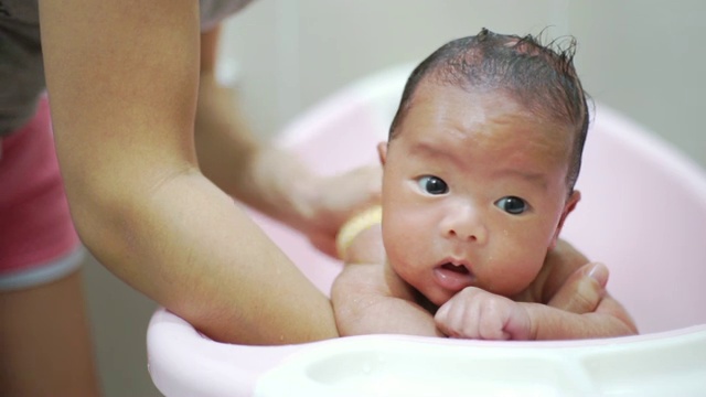 一个刚出生的婴儿正在洗粉红色的澡。视频下载
