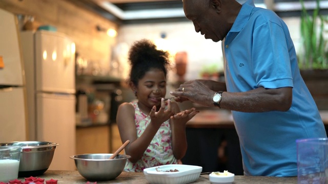 非裔拉丁美洲人的祖父在家教他们的孙子如何做饭-他们正在准备巴西旅视频素材