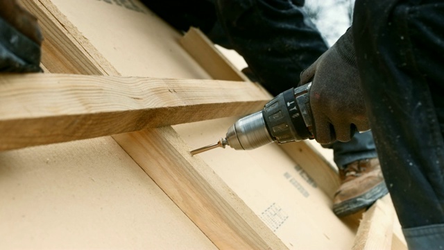 工人用机器在屋顶的木梁上钉螺丝钉视频素材
