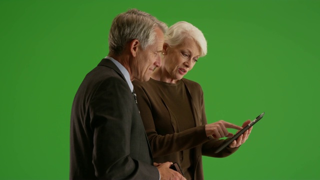 业务团队在走廊的绿色屏幕上通过平板电脑查看财务数据视频素材
