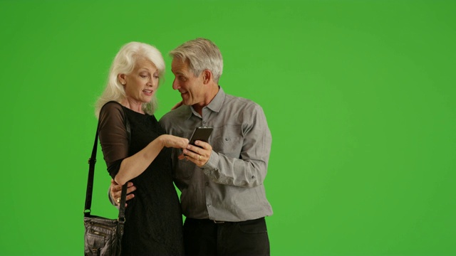 快乐的老年人晚上在绿色屏幕上一起使用智能手机视频素材