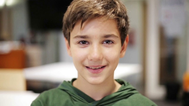 在学校教室里快乐微笑的十多岁男孩的肖像视频下载
