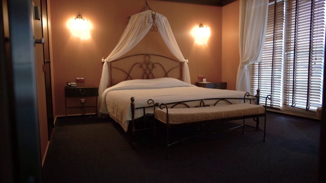 美丽的双人床站在一个小舒适的酒店房间。摄像机从左向右移动。视频下载