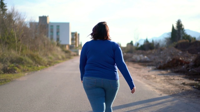 一个超重的年轻女人走在街上视频素材