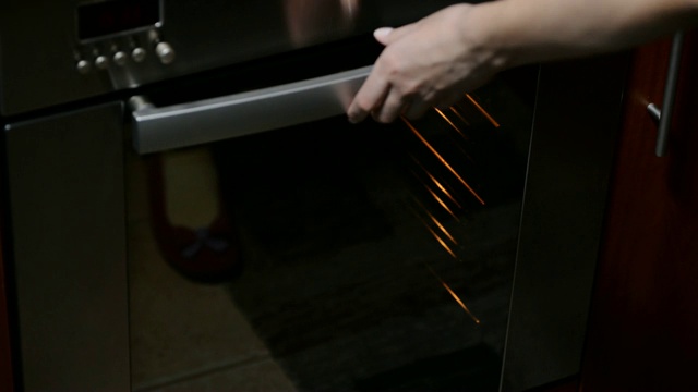 一个女性的手把一个烤盘和手工面包放入一个家庭烤箱。视频素材