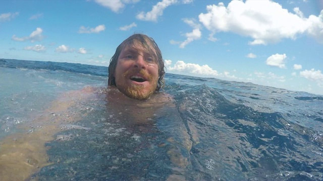 一个男人从帆船上跳下来，在太平洋里游泳。——慢动作视频下载