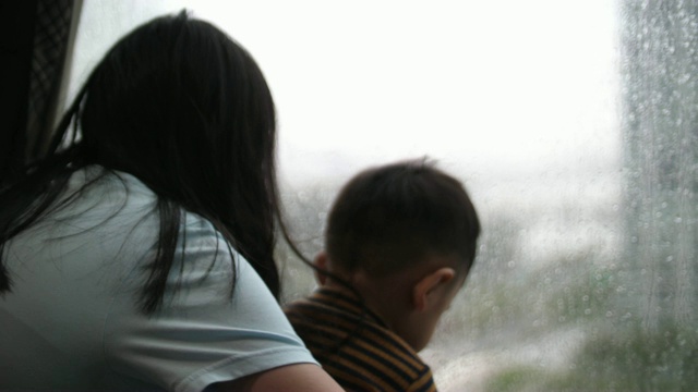 妹妹和小男孩望着窗户，下雨天视频素材