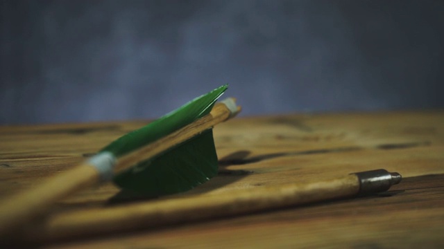 旋转老绿色木箭头在一个圆形木桌。美丽的黑色背景。中世纪的手工制作的武器。视频下载