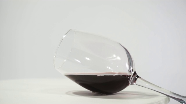 一杯红酒放在一张白色的圆桌上，旋转360度。美丽的白色背景。视频下载
