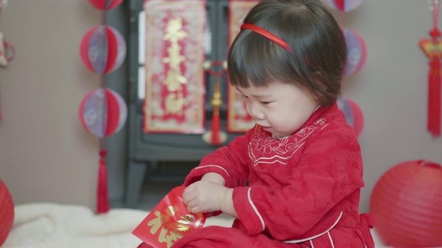 中国一个蹒跚学步的小女孩在家里庆祝春节得到红包视频素材