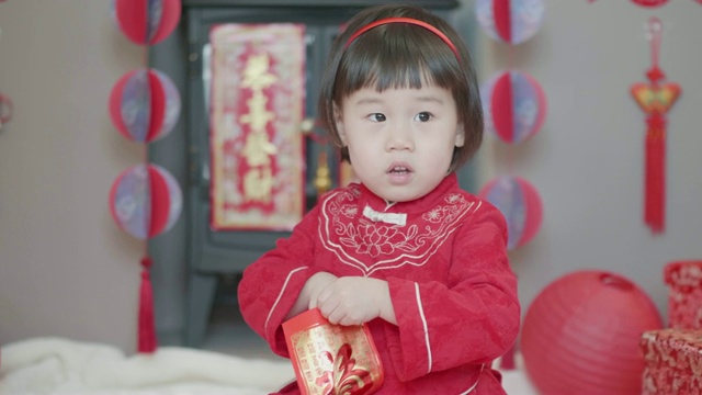 中国一个蹒跚学步的小女孩在家里庆祝春节得到红包视频素材