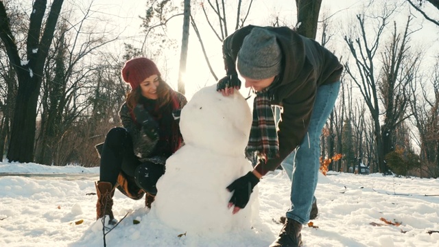 快乐的夫妇在堆雪人。视频素材