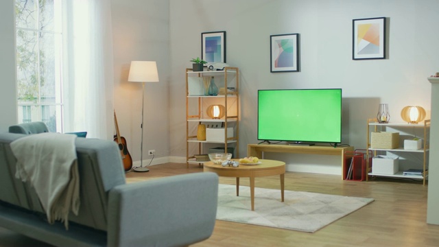 舒适的客厅与时尚的家具和设计，绿色色度键电视在房间的中央。视频下载