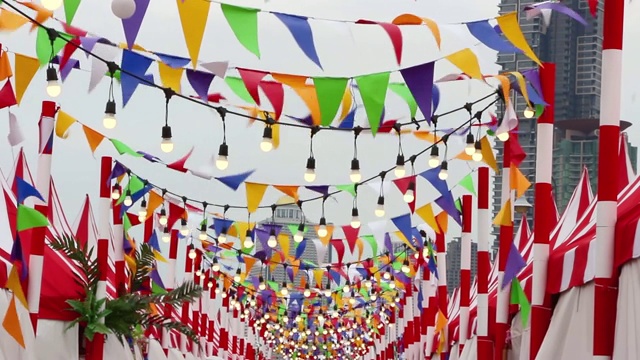 三角形的彩旗和灯泡迎风摆动。是为了庆祝欢乐而装饰的。视频下载