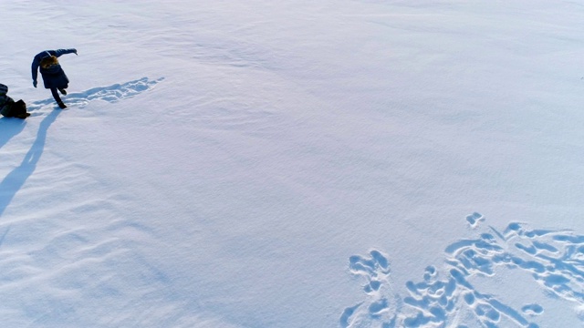 妈妈和儿子在雪地里玩耍。航拍画面，摄像机在旋转。冬天的家庭消遣。视频下载