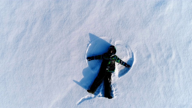 7岁男孩制作雪天使，航拍镜头。镜头慢慢接近。视频下载