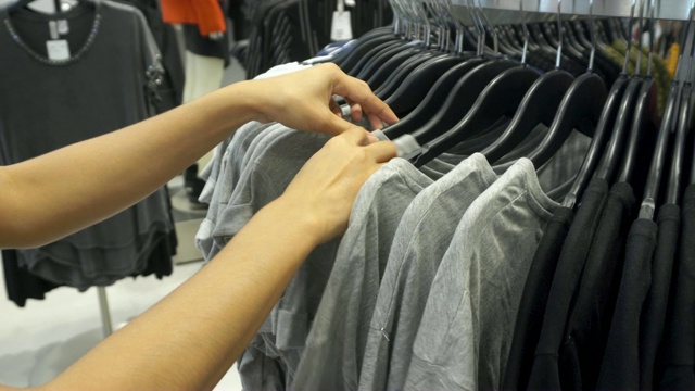 特写的女人的手拉衣架与衣服在商店。购物的概念视频素材