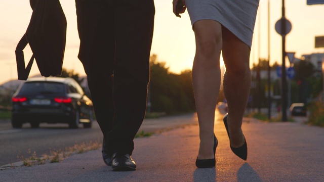 低角度:日出时分穿着高跟鞋走路上班的一男一女视频素材