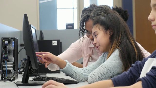 小学志愿者在计算机实验室指导小女孩视频素材