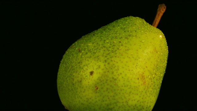 一个成熟多汁的梨与水滴的特写。视频下载