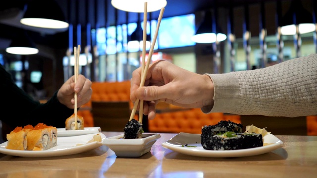 幸福的夫妇在日本餐厅，寿司吧吃寿司卷。视频素材