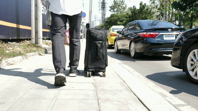 一个年轻人在街上拖着一个手提箱视频素材