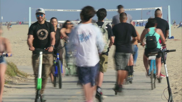 在加州威尼斯海滩拥挤的自行车道上，数十人骑着自行车、电动摩托车和其他移动设备锻炼视频素材