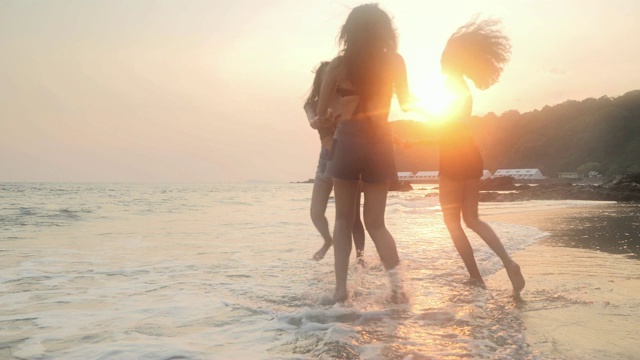 亚洲三个年轻的女性朋友有乐趣在日落海滩。海滩度假旅游概念。cinemagraph旅行视频下载