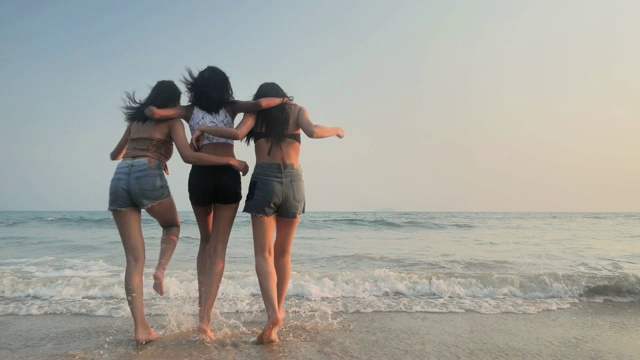 亚洲三个年轻的女性朋友有乐趣在日落海滩。海滩度假旅游概念。cinemagraph旅行视频素材
