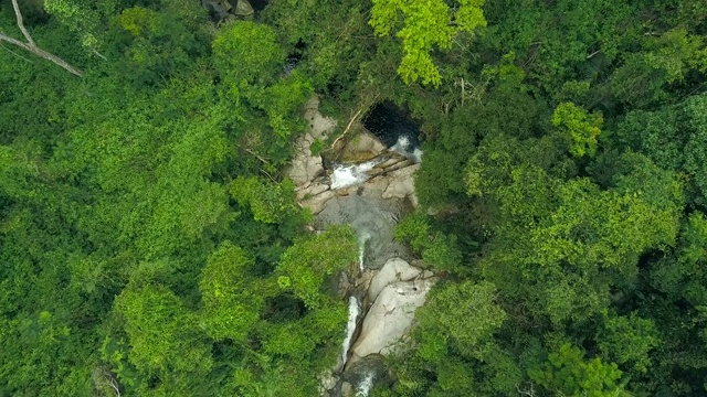 鸟瞰图热带河流流动的石崖在野生雨林。无人机在丛林中观看岩石河和热带瀑布的水流。野生自然景观视频素材