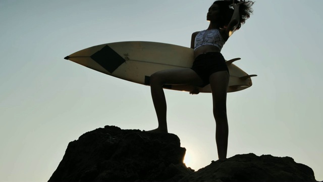 肖像剪影美丽的冲浪者女孩在海滩上日落。体育cinemagraph视频素材