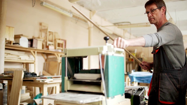 熟练成熟的木匠在他的工作室使用木工机器打磨长木板视频素材