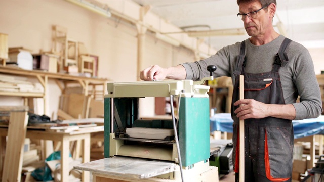 熟练成熟的工匠在他的家具制作车间用木工机器打磨长木板视频素材