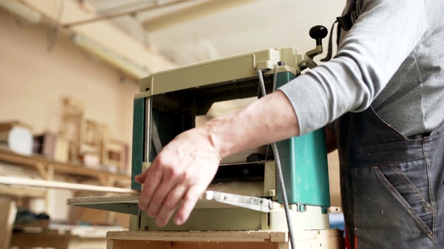 专业家具制造商测量木板，并在他的车间用木工机器打磨它视频素材