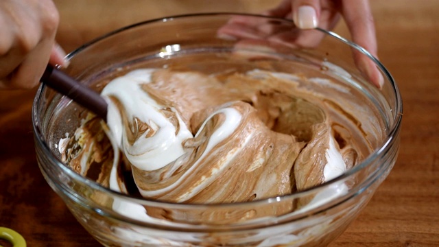 女人的手搅拌奶油和巧克力，准备做蛋糕。视频素材