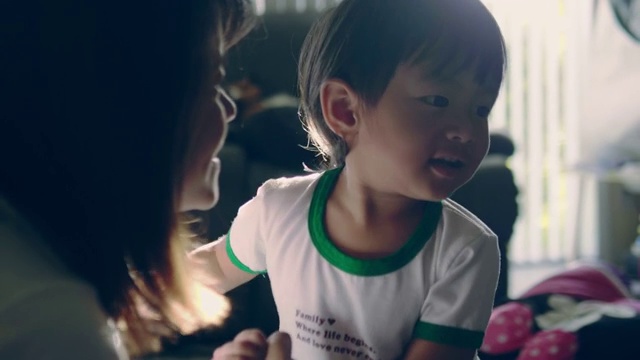 年轻的亚洲母亲和婴儿在沙发上接吻。视频素材