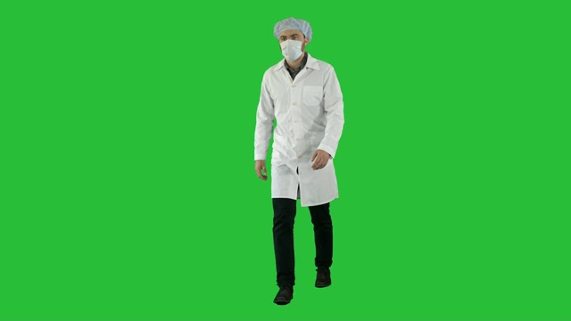 行走的年轻男医生戴着口罩和医疗帽在绿色屏幕上，Chroma Key视频素材